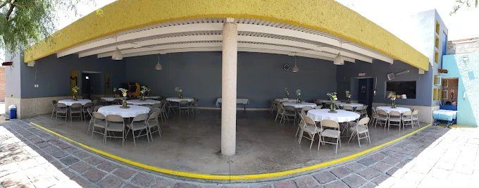 Terraza techada con mesas redondas vestidas de blanco
